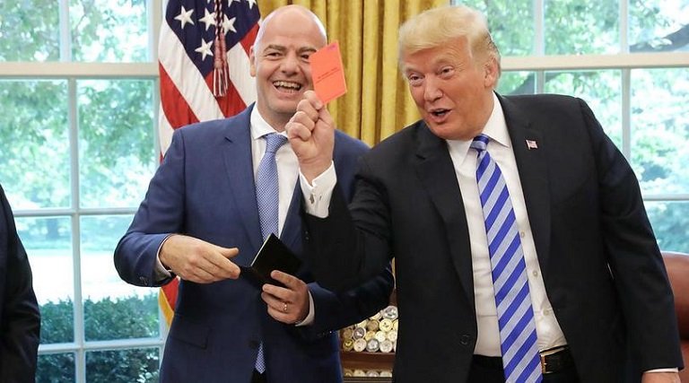 President Donald Trump shows the media a red card during a visit by FIFA boss Gianni Infantino