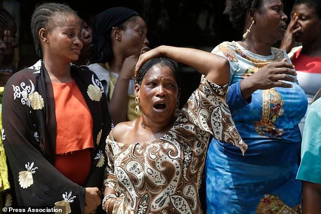 A woman cries as a body of child is recovered from the rubble (Sunday Alamba/AP)