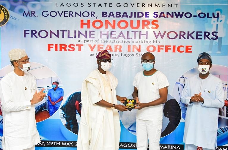 Lagos State Commissioner for Health, Prof. Akin Abayomi; Governor Babajide Sanwo-Olu, presenting a plaque to a Frontline Health worker, Dr. Sunday Oluseyi Adesola - Principal Medical Officer 1 at Isolation Centre, Mainland Hospital Yaba