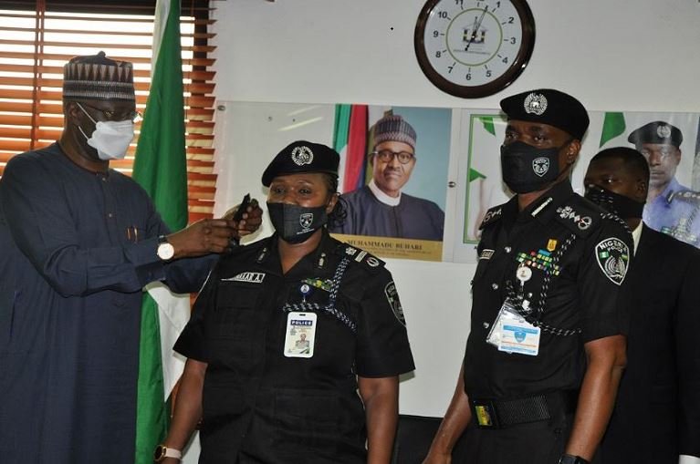 SGF Boss Mustapha decorating a senior police officer as IGP Adamu looks on police commissioners