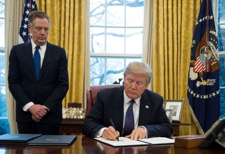 President Donald Trump signs a document in the Oval Office