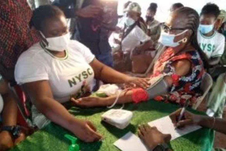 NYSC corps member offering medical aid to a resident of the community