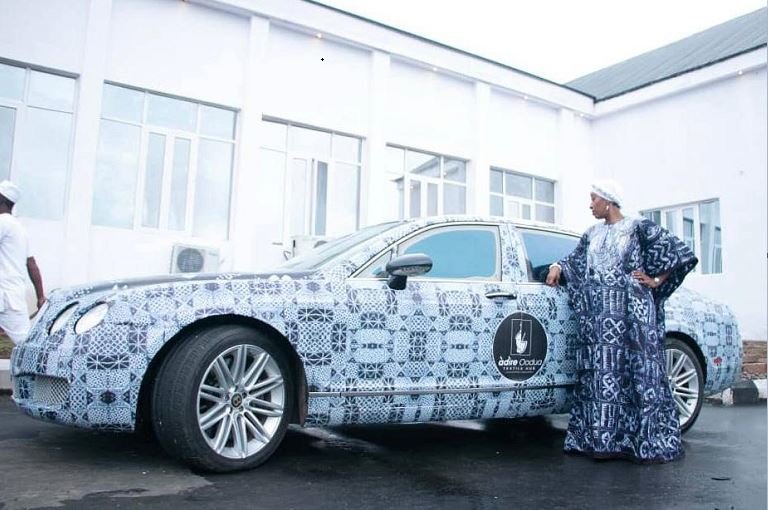 Princess Ronke Ademiluyi, CEO of Adire Oodua Textile Hub stands next to Ooni's branded Bentley