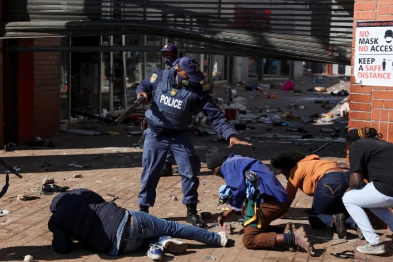 A police officer detains demonstrators in Katlehong, South Africa, today as protests continue following the imprisonment of former South African president Jacob Zuma Soweto