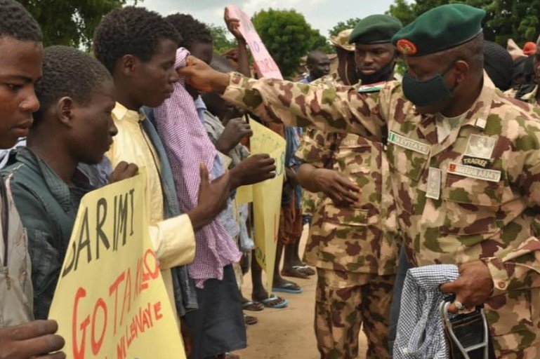 Military officers hand clothes to repentant Boko haram terrorists handed