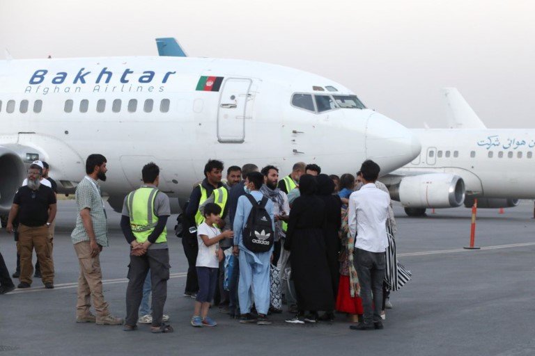 Dual-nationality passengers who have missed their flight for Qatar speak with an airport official at the international airport in Kabul, Afghanistan