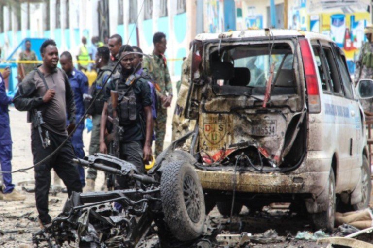 Civilians and Somalian security officers gather at the scene of a suicide car bomb at a street junction near the president's residence, in Mogadishu, Somalia