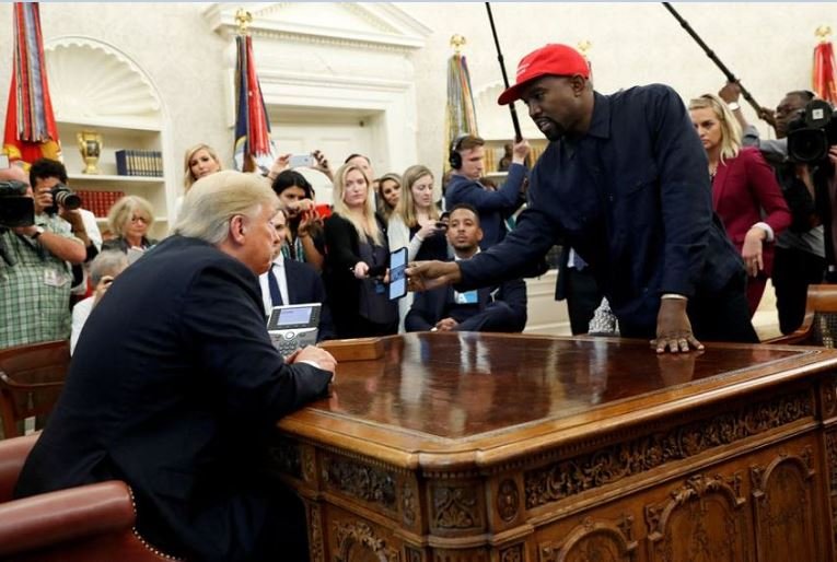 Rapper Kanye West shows President Donald Trump his mobile phone during a meeting in the Oval Office at the White House in Washington, U.S., October 11, 2018. REUTERS/Kevin Lamarque
