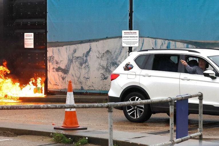 A man throws an object out of a car window next to the Border Force centre after a firebomb attack in Dover, Britain UK