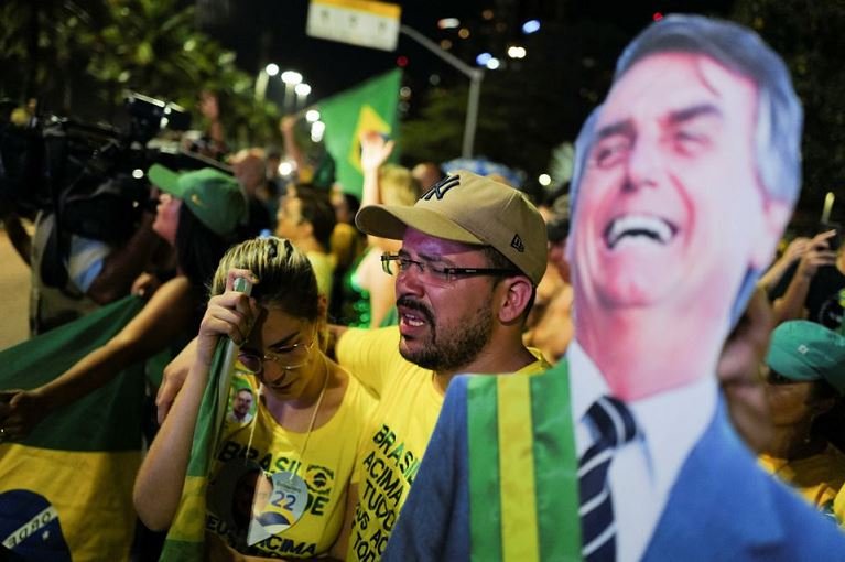 Supporters of Brazil's President Jair Bolsonaro react next to a cardboard figure of Bolsonaro between while gathering with others outside his home, in Rio de Janeiro, Brazil