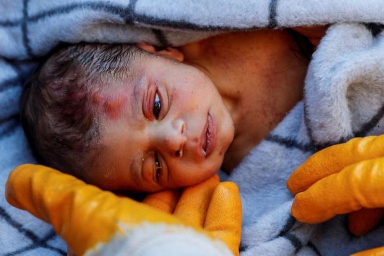 A rescuer holds baby boy Kerem Agirtas, a 20-day-old survivor who was pulled from under the rubble, in the aftermath of a deadly earthquake in Hatay, Turkey